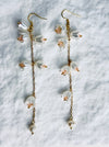 Floral earrings with gold chains on a textured white background