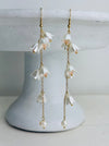 Floral earrings with gold chains on a white stand