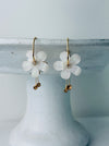White floral hoop earrings with gold-tone hoops and sparkling crystal accents.