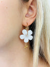 White floral hoop earrings with gold-tone hoops and sparkling crystal accents.