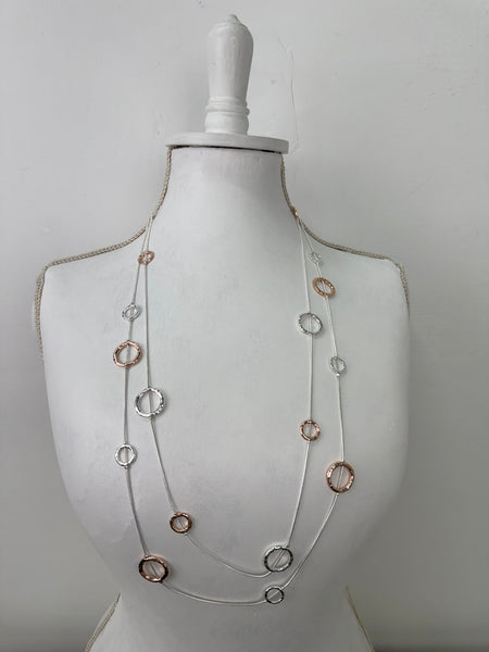 long silver and rose gold necklace with textured circle charms displayed on mannequin