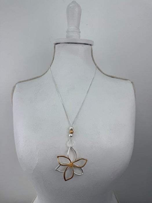 Necklace with a floral pendant on a mannequin bust against a plain background