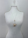 Mannequin wearing a white dress with a gold floral brooch on a light gray background