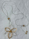 Gold and silver floral pendant on a string against a light gray background