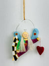 Handmade wooden decorative angel ornament with colourful dress and a heart. Comes with a gold string, displayed on a white background