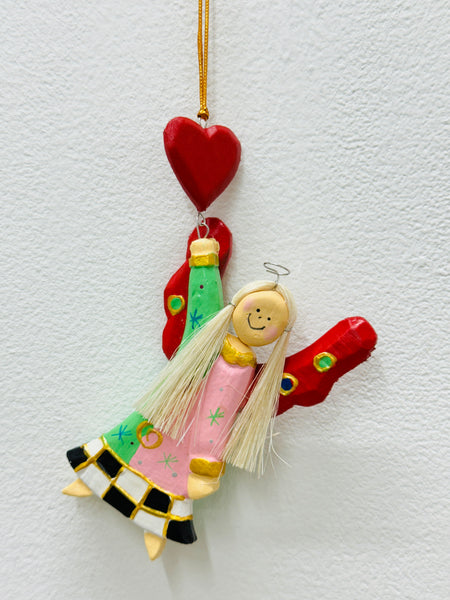 Hand-painted wooden hanging angel with pink dress, green accents and red heart on a gold string.