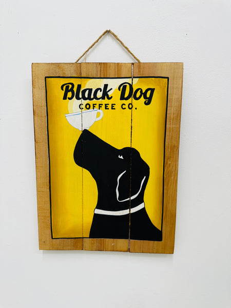 Hand-painted Black Dog wooden sign with yellow background, dog and coffee cup illustration, and hanging rope on white background.