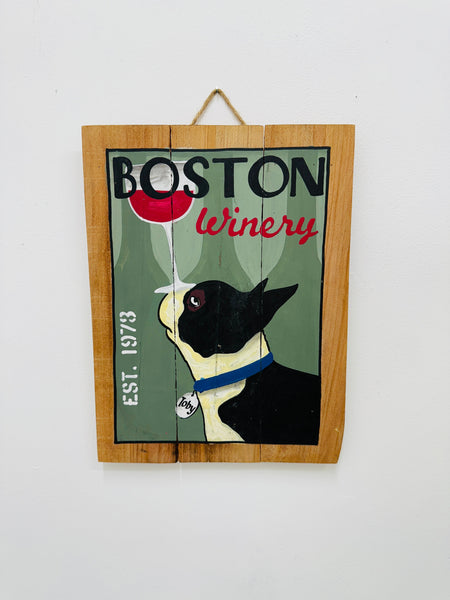 Hand-painted Boston Winery wooden sign with dog and wine glass illustration and hanging rope on white background.