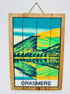 Hand-painted Grasmere wooden sign with mountain landscape illustration and hanging rope on white background.