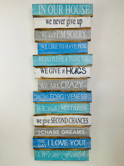 Hand-painted In Our House wooden sign with inspirational phrases and hanging rope on white background.