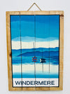 Hand-painted Windermere wooden sign with lake landscape illustration and hanging rope on white background.