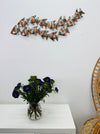 Zebra fish shoal metal wall art displayed above table in coastal interior.