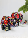 display view of small and large black wooden flower elelphants on white surface