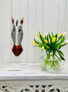 display view of zebra wood mask on wall next to a flower vase