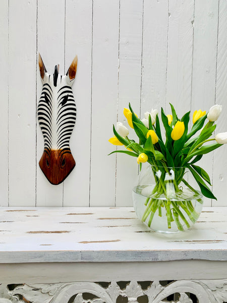 display view of zebra wood mask on wall next to a flower vase