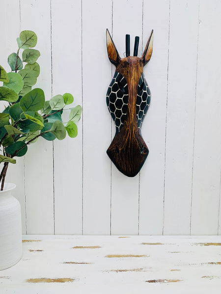 display view of wooden giraffe mask on wall