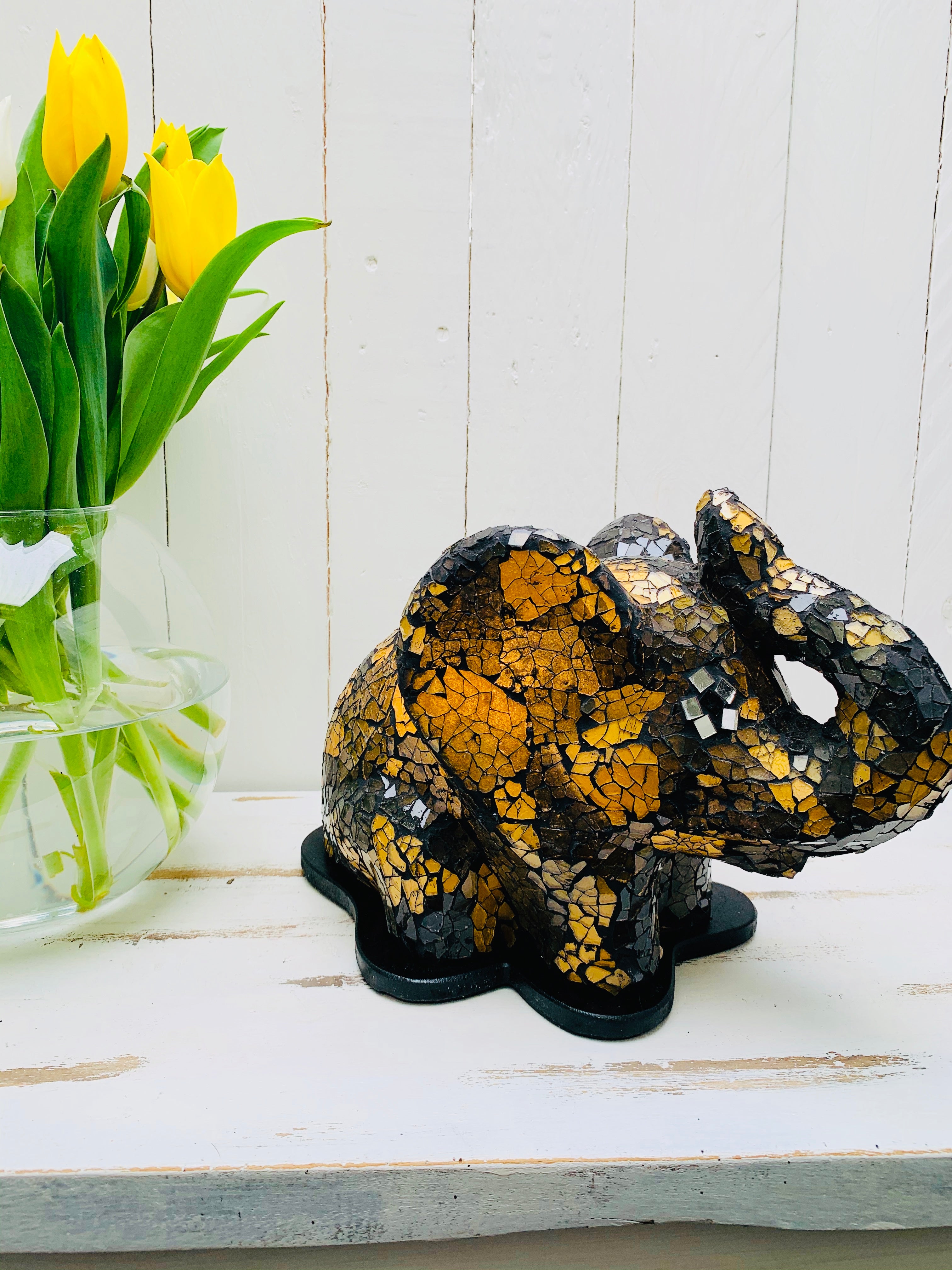 display view of mosaic elephant lamp next to a vase of flowers