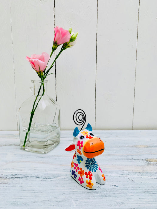 display view of wooden flower cow next to a vase of flowers