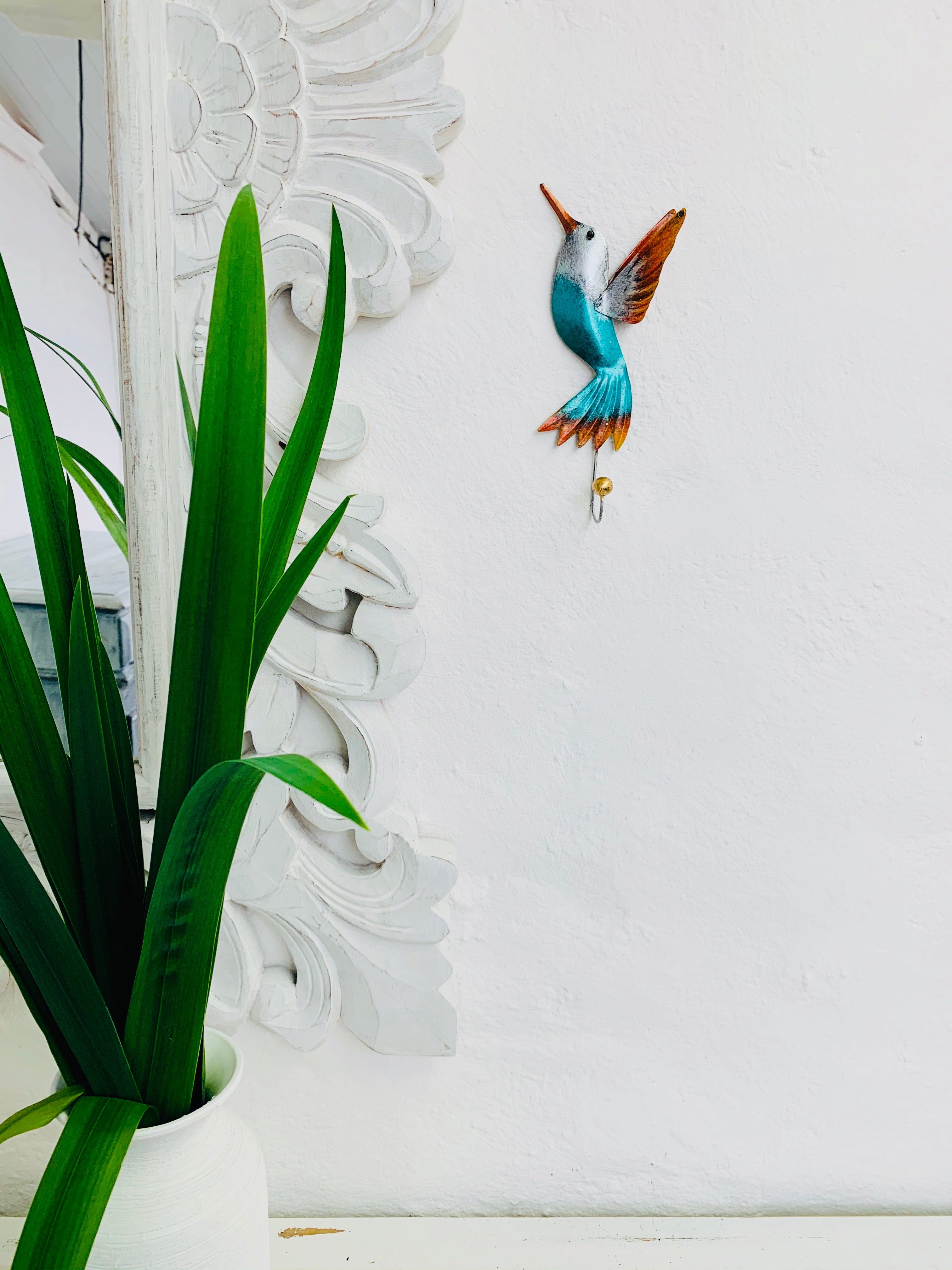 display view of hummingbird hook attached to the wall by a green plant