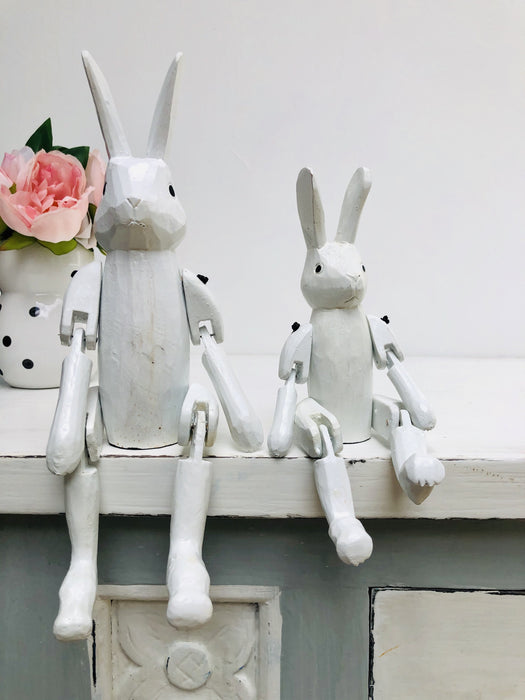 display view of small and large white wooden bunnies sat on white surface