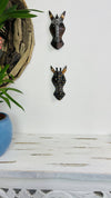 set display view of two zebra and giraffe masks on wall 