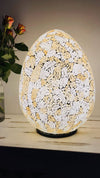front view of mosaic egg lamp with light on in dim lit space