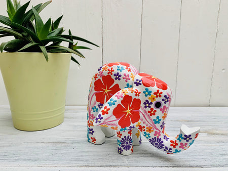 display view of wooden flower elephant in white next to a plant pot on a white wooden surface