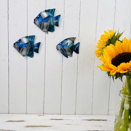 Blue metal banner fish wall art displayed on a white panel wall with a sunflower