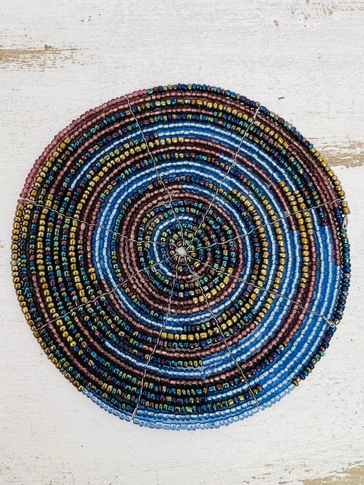 A round, handmade beaded coaster featuring a spiral pattern with colors including blue, gold, and other shades