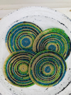 Set of lime green and blue beaded coasters arranged together on a light wooden background.