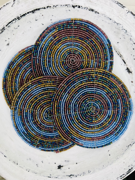 Set of ocean blue, gold and olive beaded coasters arranged together on a light background.