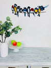 Handmade metal birds on a wire wall decoration with multicoloured detailing above a wooden table