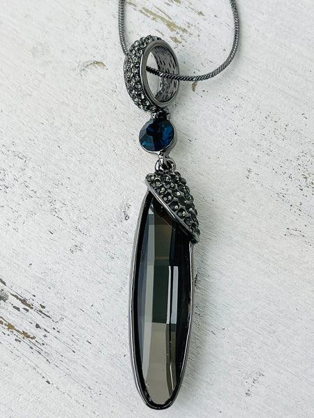 A long silver necklace with an elegant Art Deco style pendant, featuring gunmetal grey plating and a blue accent.