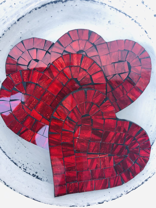 Cherry Red heart-shaped mosaic coasters with deep red hand-painted glass pieces on MDF base, photographed from above on a light textured surface.