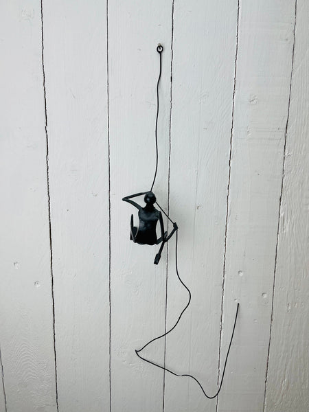 Wall-mounted metal climbing man sculpture shown from mid-distance