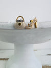 A pair of stud earrings featuring one in the shape of a high heel shoe and the other in the shape of a handbag, both detailed with crystals.