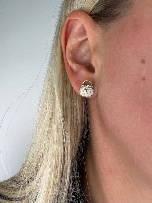 Close-up of a person wearing stud earrings with a plain background