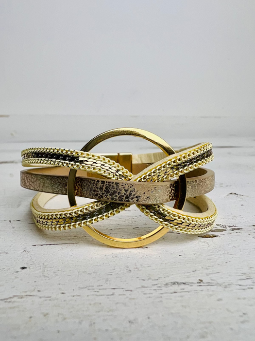 A gold-colored bracelet with faux snake skin detail, displayed on a white background.