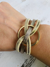 Gold bracelets on a wrist against a light background