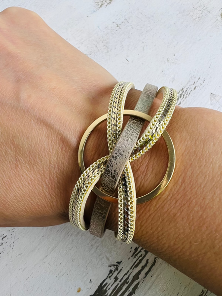 Gold bracelets on a wrist against a light background