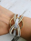 A bracelet with white gold and faux snake skin detail worn on a person's wrist.