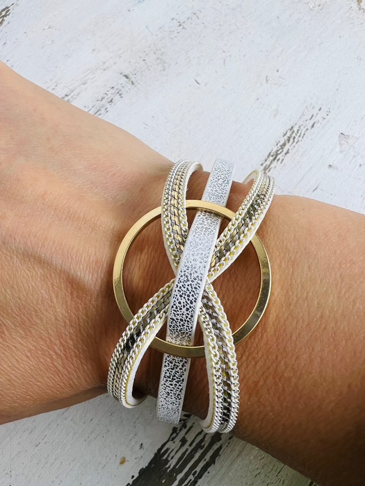 A bracelet with white gold and faux snake skin detail worn on a person's wrist.