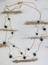 A double strung necklace with black crystal cubes on a wooden surface.