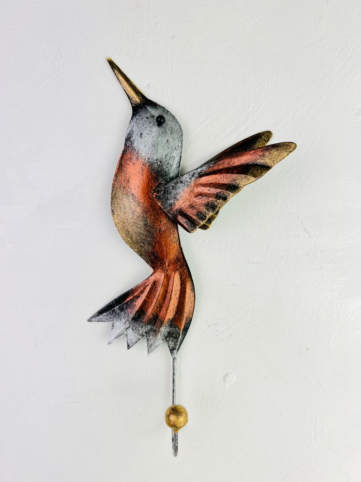 Handmade and hand painted copper humming bird hook with silver and gold detailing, mounted on a white wall.