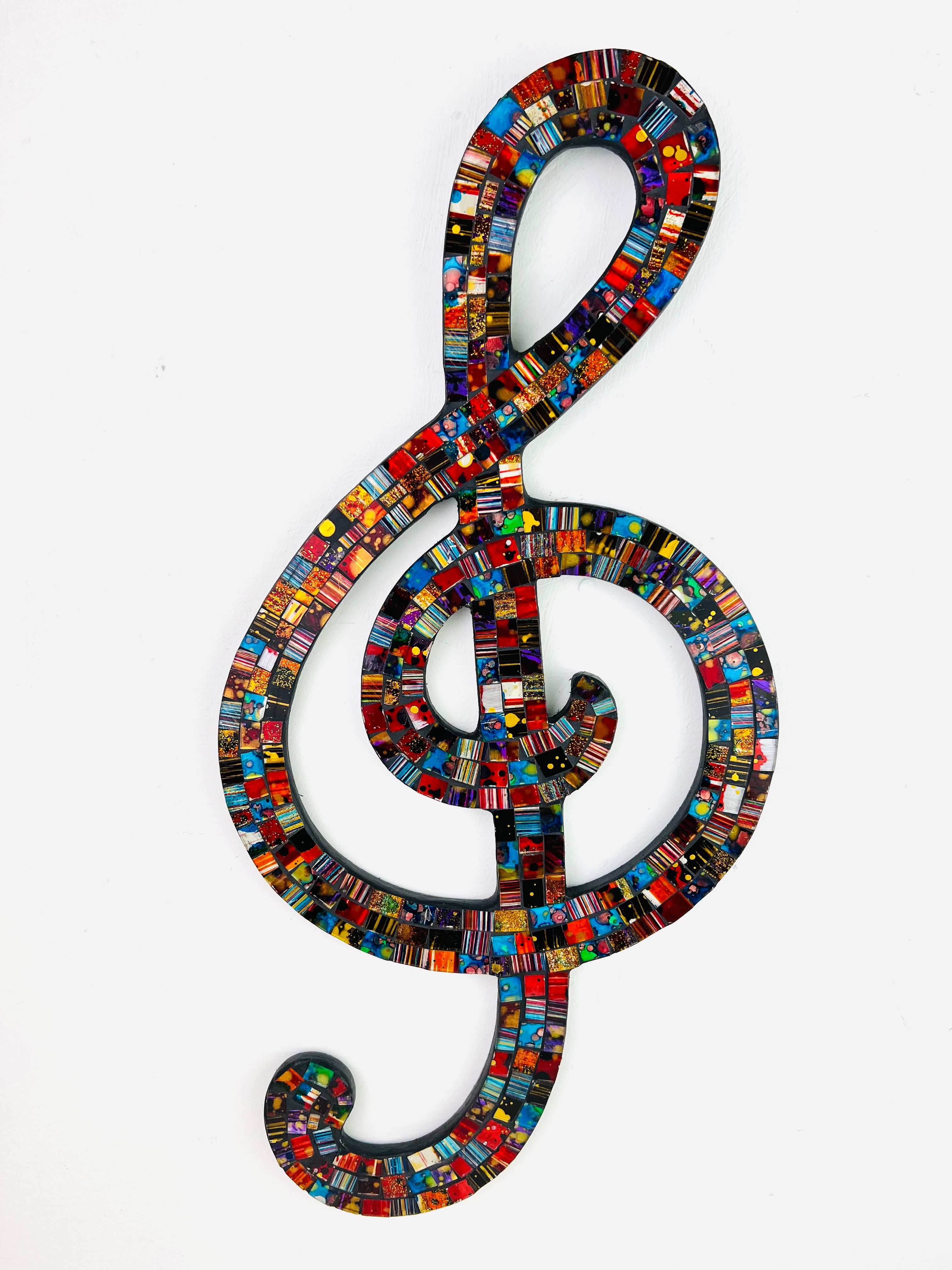 front view of mosaic treble clef in multi colours on white background