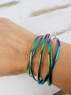 A multicolored iridescent cuff bracelet displayed on a person's wrist.
