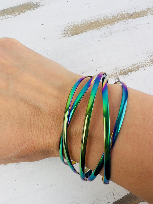 A multicolored iridescent cuff bracelet displayed on a person's wrist.