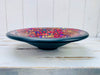 Side view of handmade mosaic glass bowl in Violet Burst colours showing curved terracotta base and glossy red and purple surface.