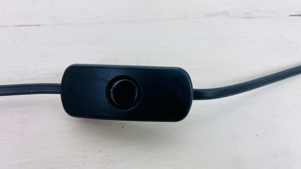 Close-up of black inline switch and cable with UK plug on white wooden background for handmade mosaic lamp.