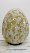 Mosaic egg lamp switched off on white background, displaying detailed gold and silver mosaic glass pattern.